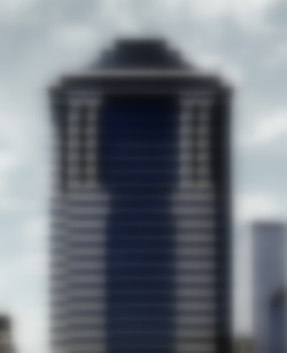 The crown of 60 Wall Street: banded stone piers, flared capitals, blue-green glass and its dark hipped cap.
