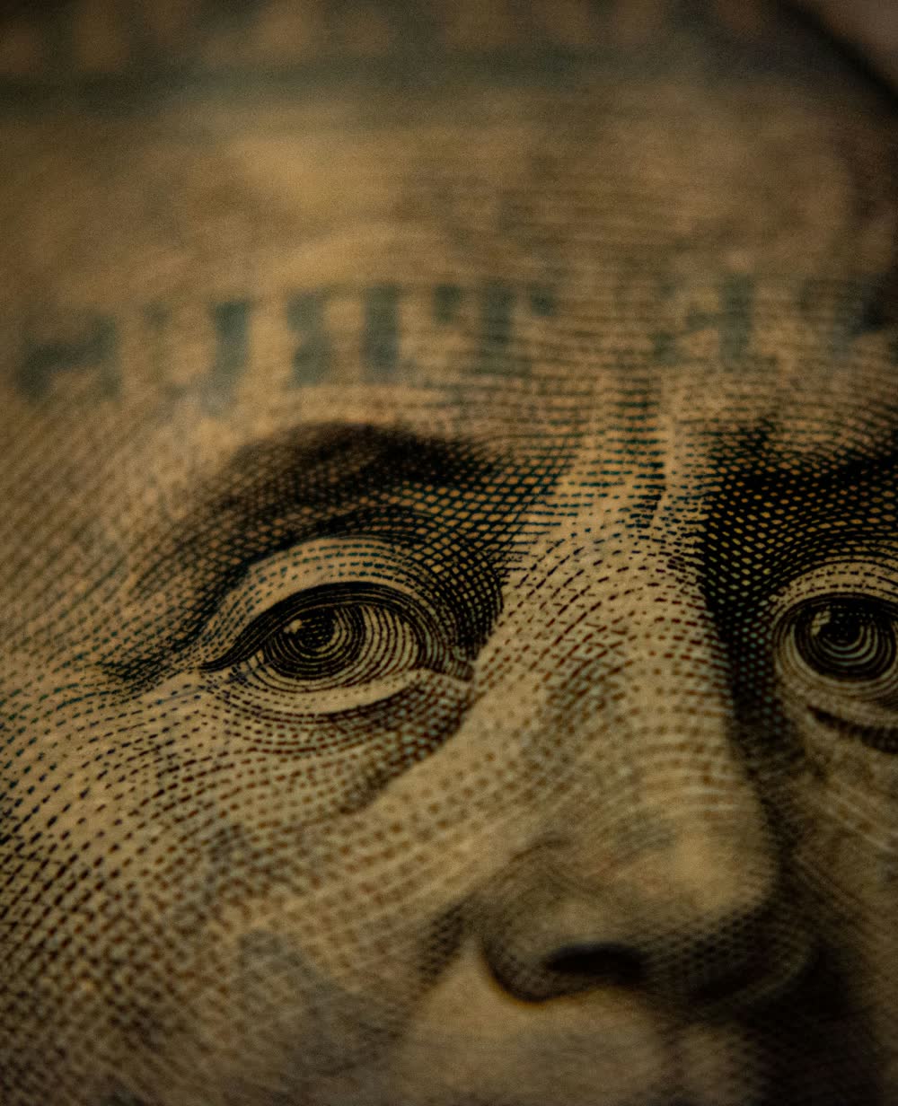 An engraved eye from the portrait of Benjamin Franklin on a United States hundred dollar note.