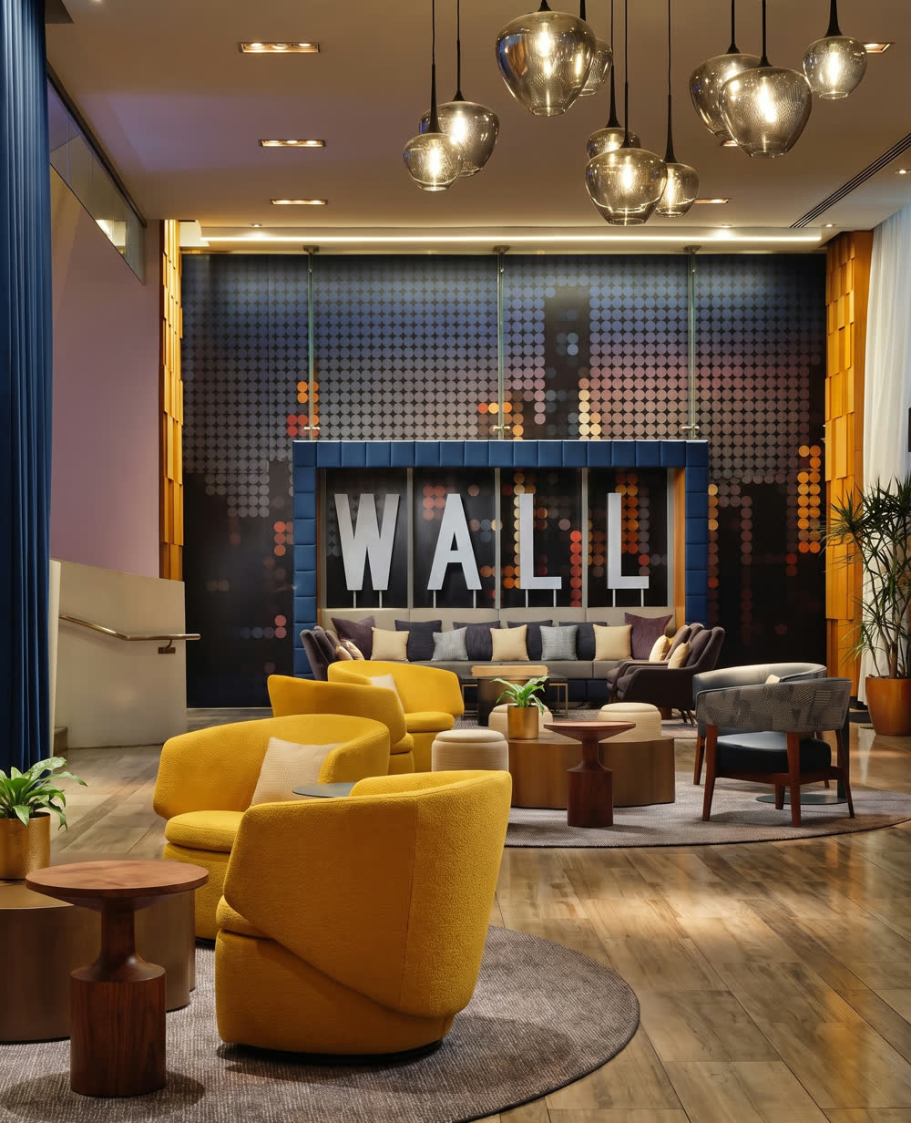 A hotel lobby lounge with tall letters spelling WALL above a blue banquette.