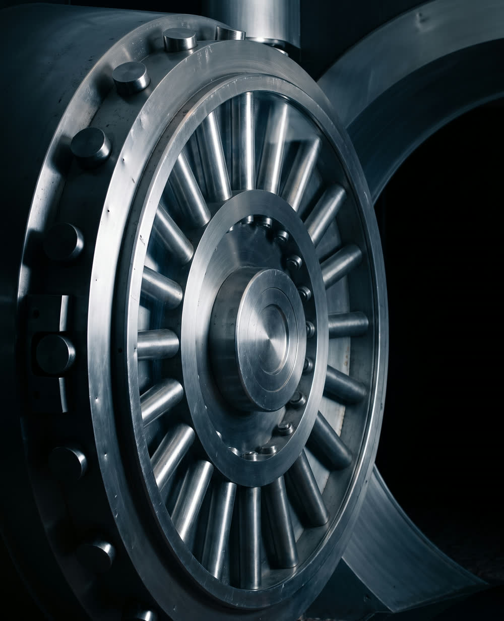 A circular bank vault door of machined steel.