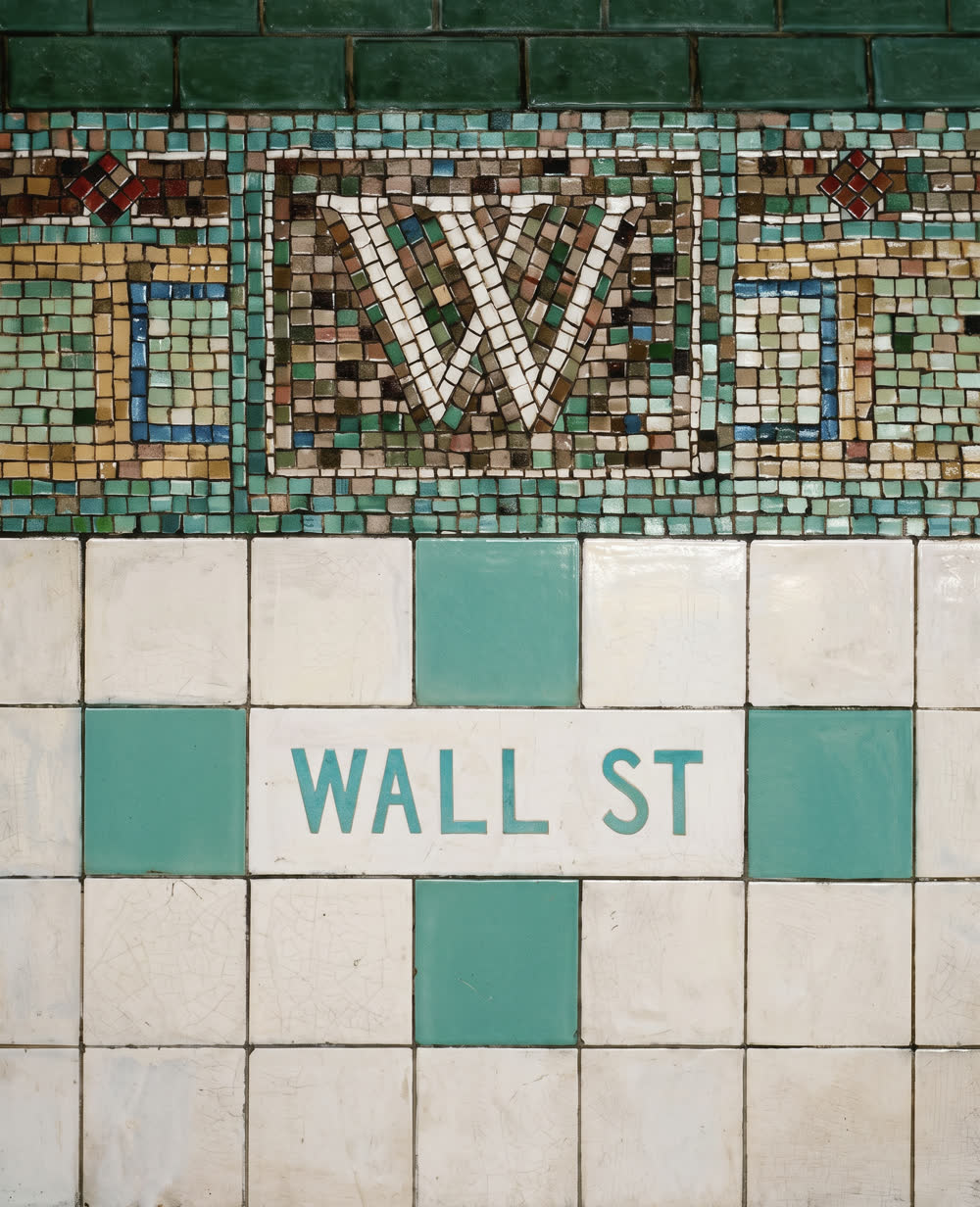 The WALL ST station-name marker in glazed tile, below a mosaic band carrying a letter W.