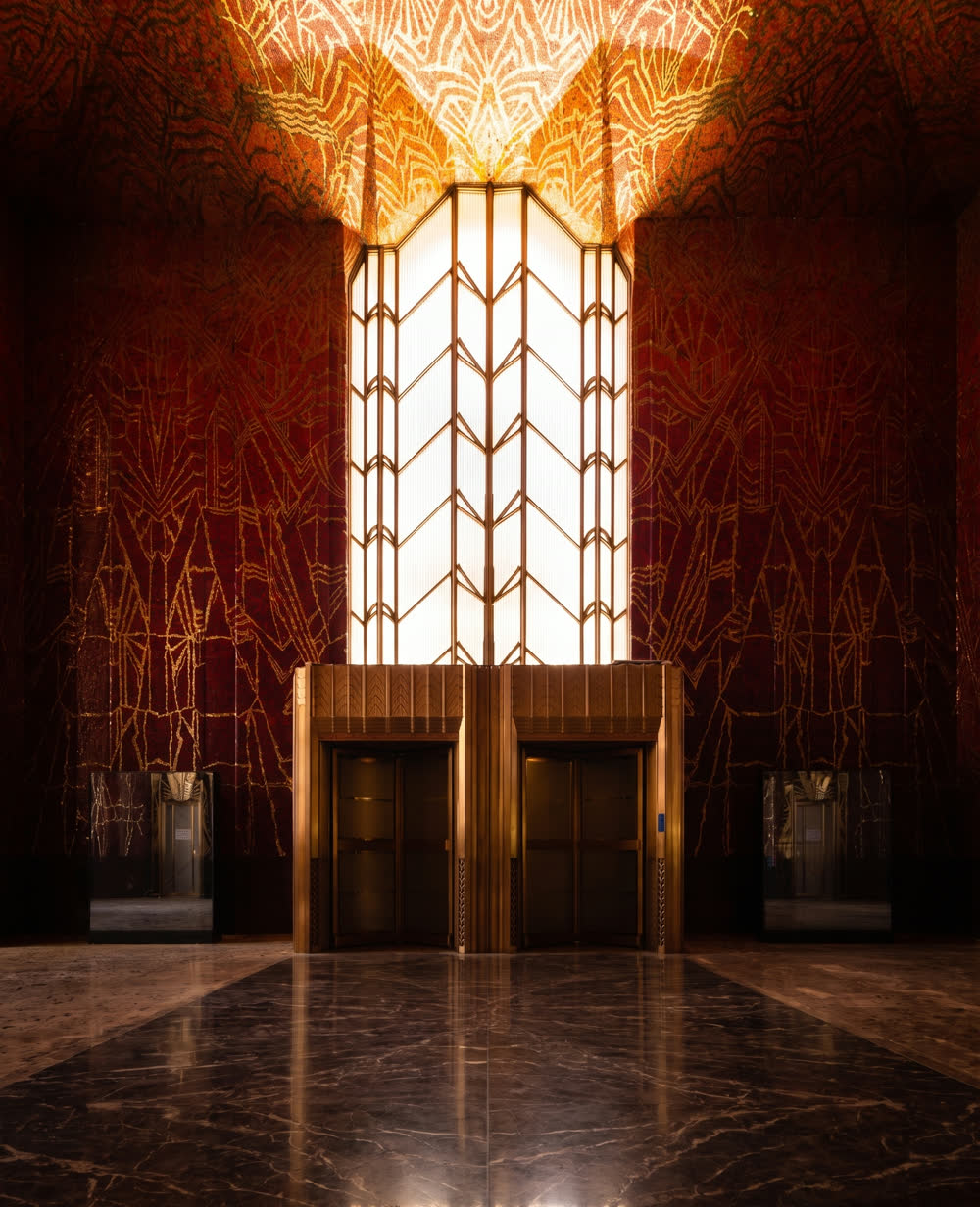 The mosaic elevator lobby of the Red Room at One Wall Street, lit by its central glass screen.