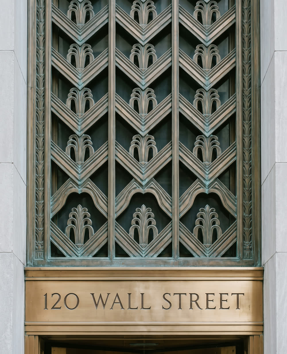 A cast bronze art deco entrance grille above a polished bronze lintel.